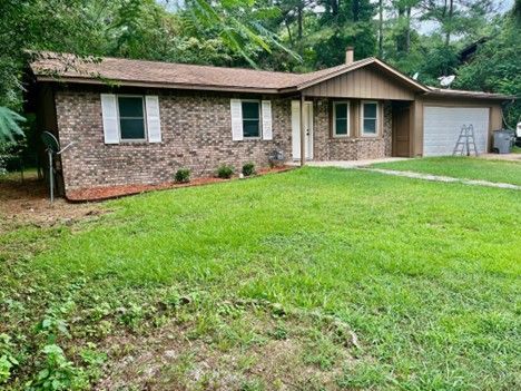 A brick house with a large lawn in front of it.