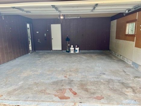 An empty garage with a door open and a window.