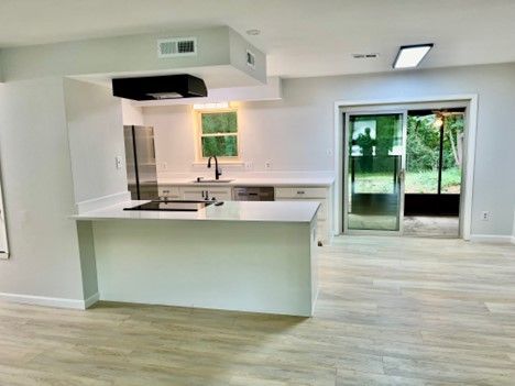An empty kitchen with a large island and sliding glass doors.