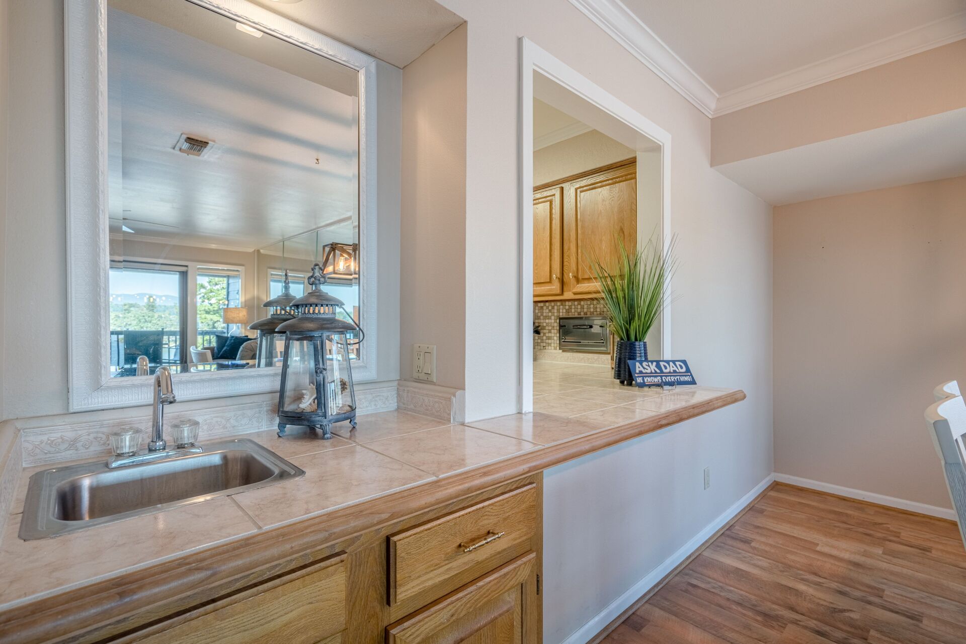 A kitchen with a sink , cabinets , and a mirror.