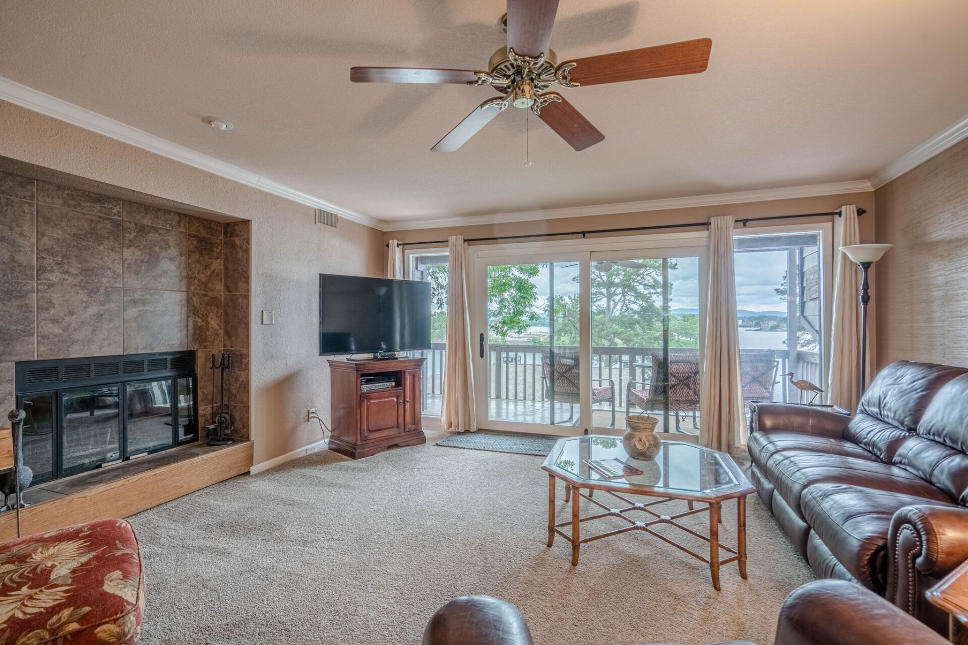 A living room with a couch , fireplace , television and ceiling fan.