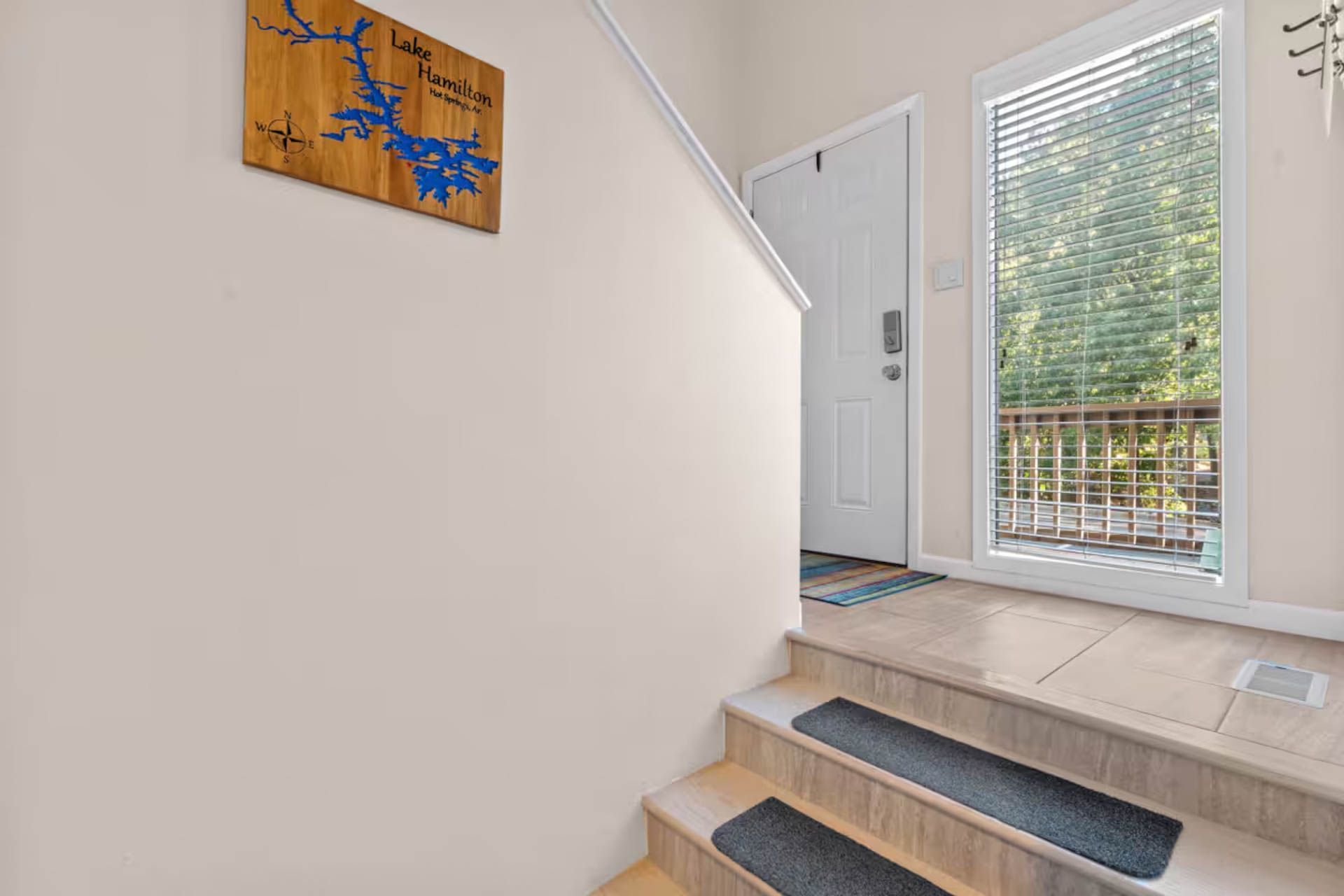 Staircase leading to a white door and a sliding glass door with a view of a deck and trees.