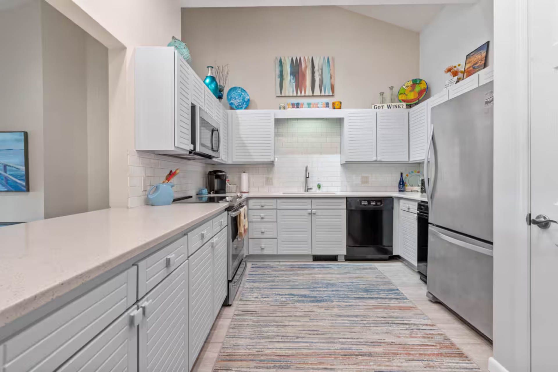 White kitchen with cabinets, appliances, and a rug.