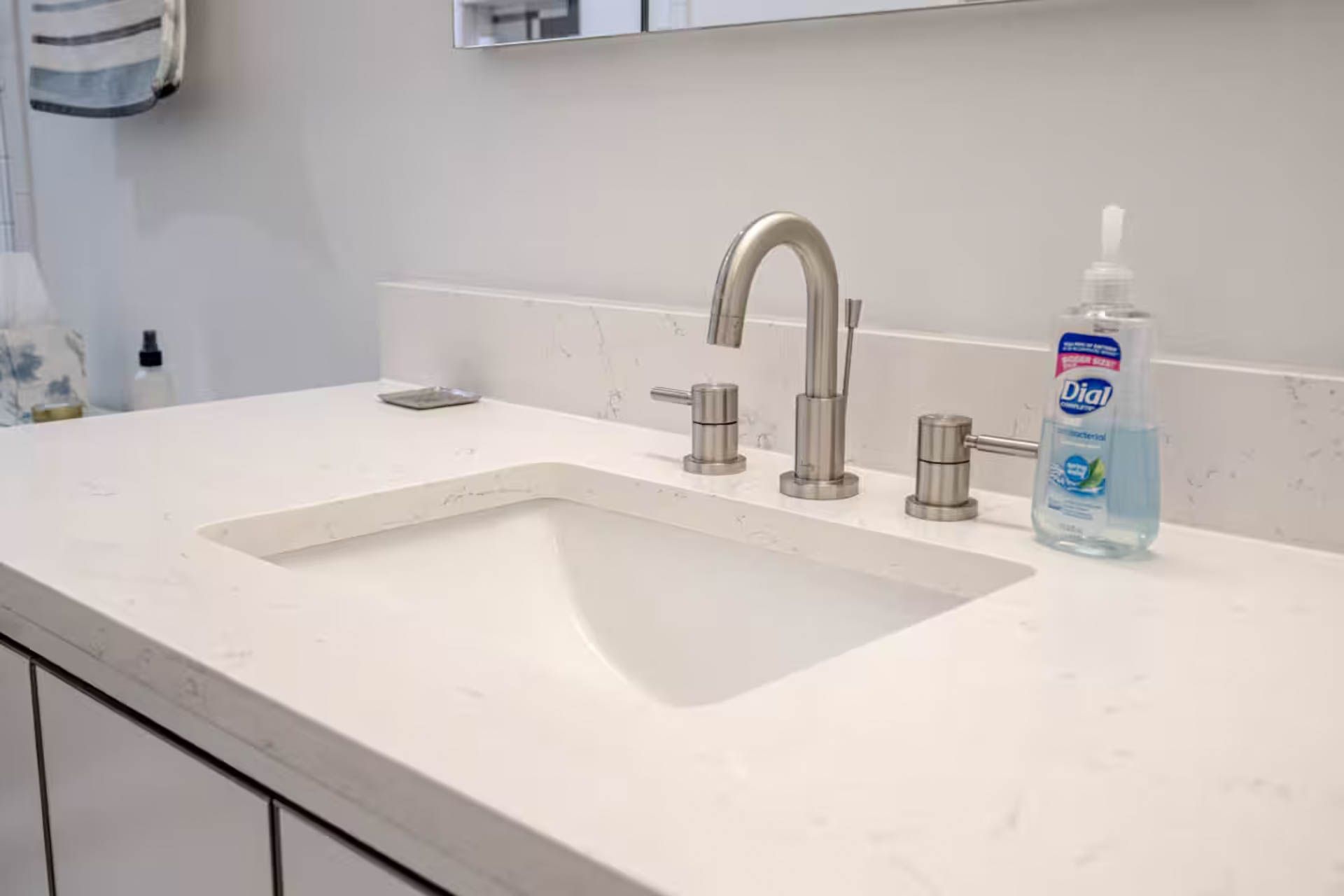 Bathroom sink with faucet, soap dispenser, and white countertop.