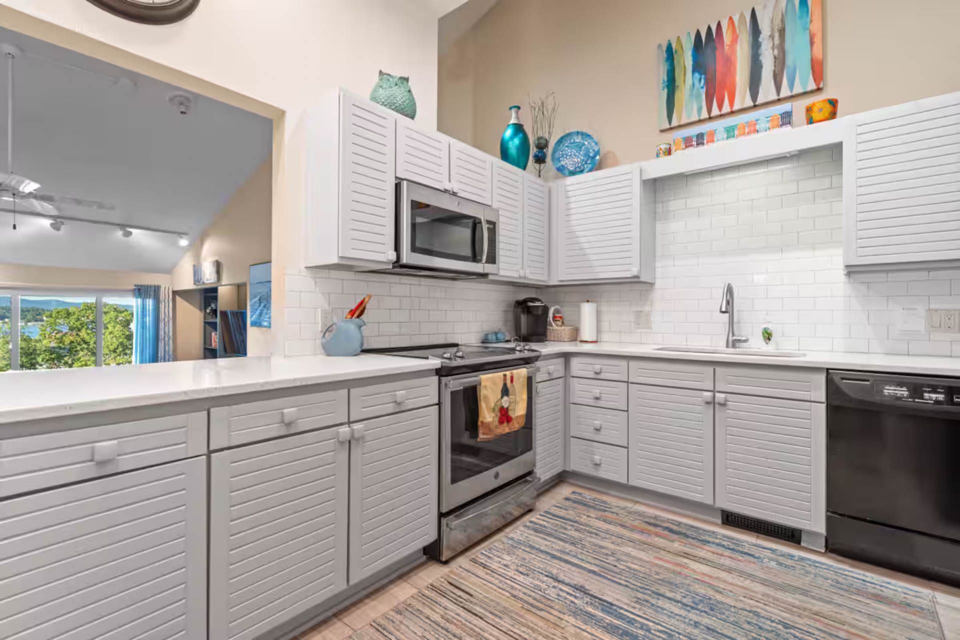 Modern kitchen with white cabinets, stainless steel appliances, and colorful wall art.