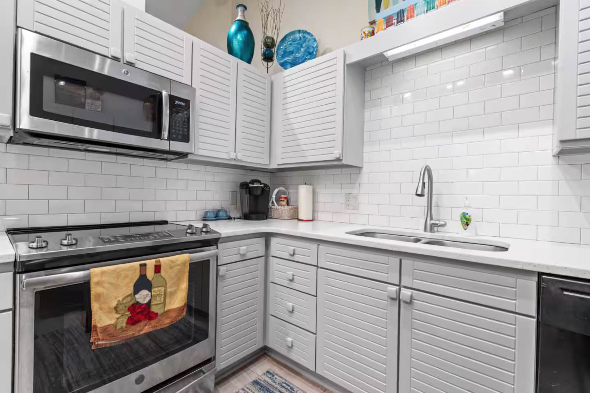 Gray and white kitchen with stainless steel appliances, white subway tile backsplash, and light gray cabinets.