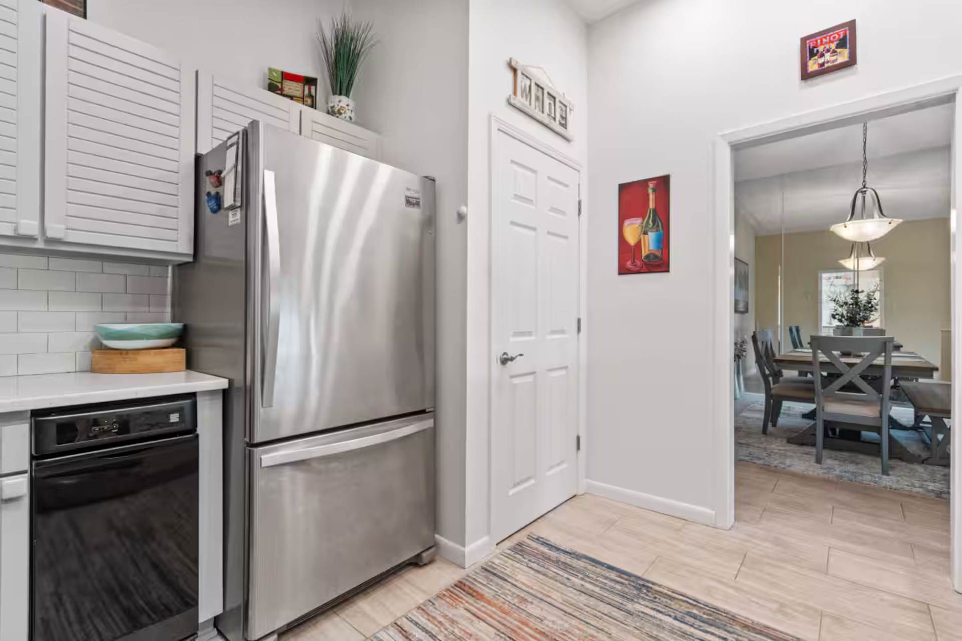 Kitchen with stainless steel refrigerator, white cabinets, and doorway to dining area.