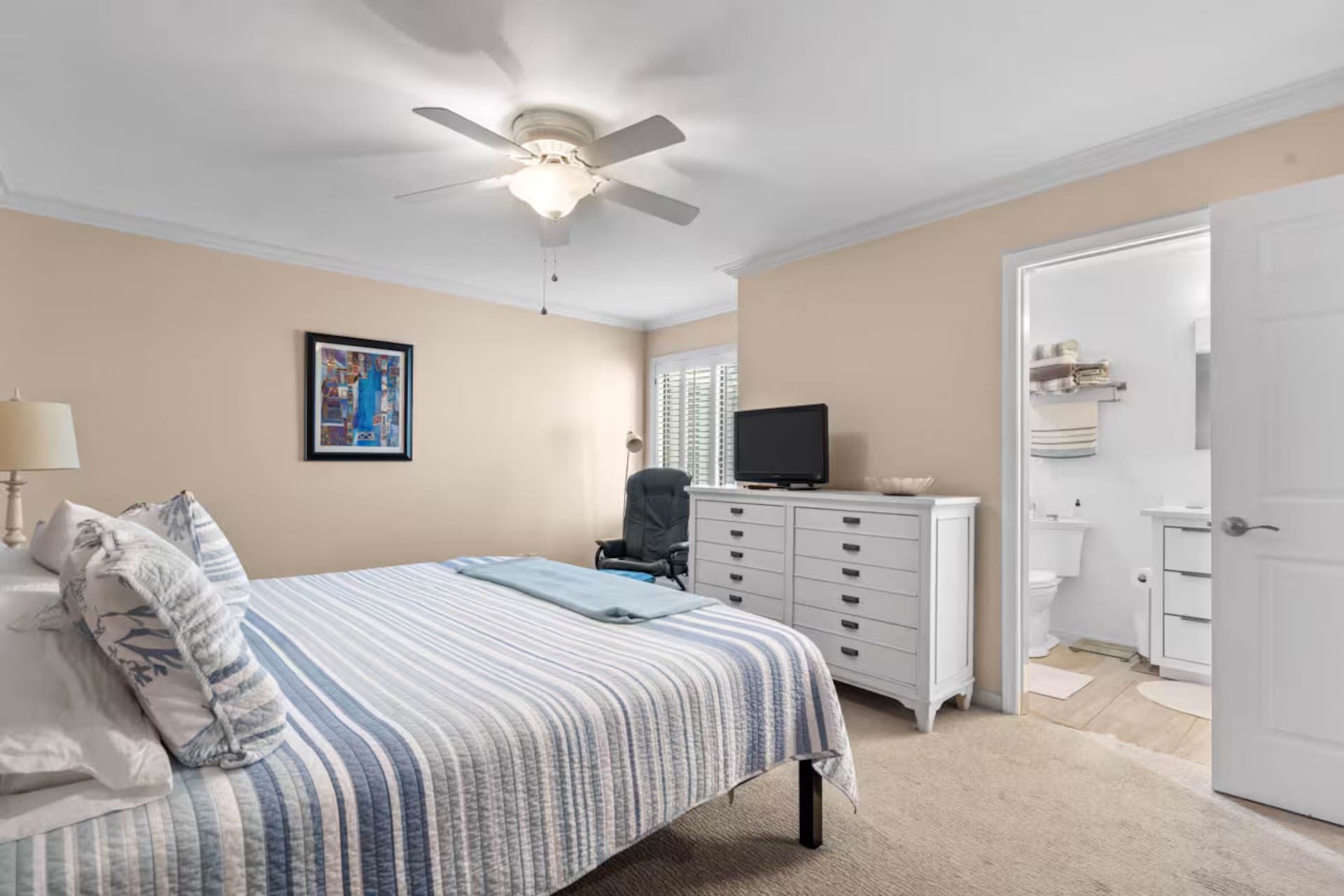 Bedroom with bed, white dresser, and open door to a bathroom.