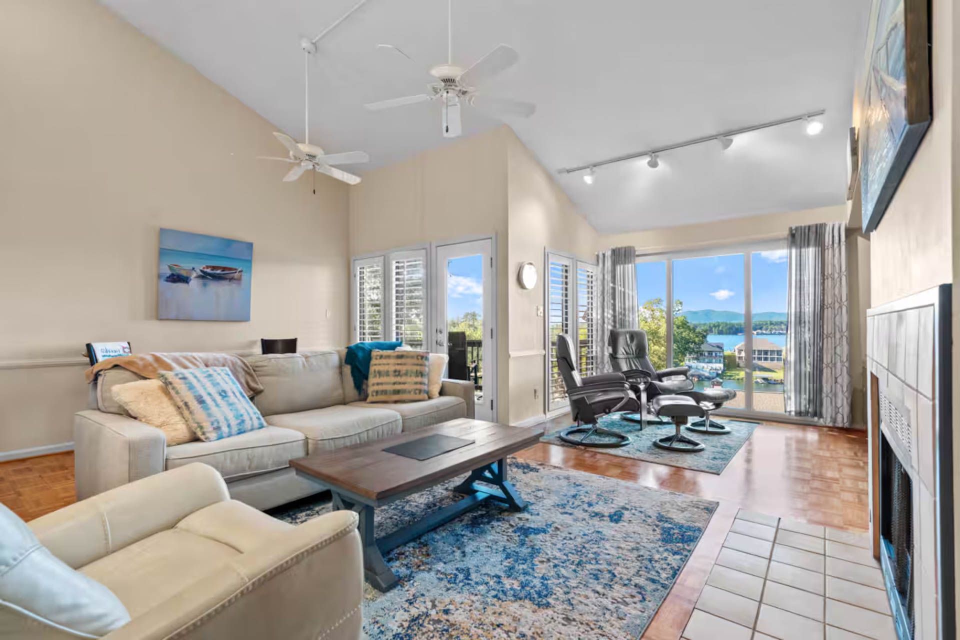Living room with tan walls, light wood floors, large windows with a lake view, and a beige sofa.