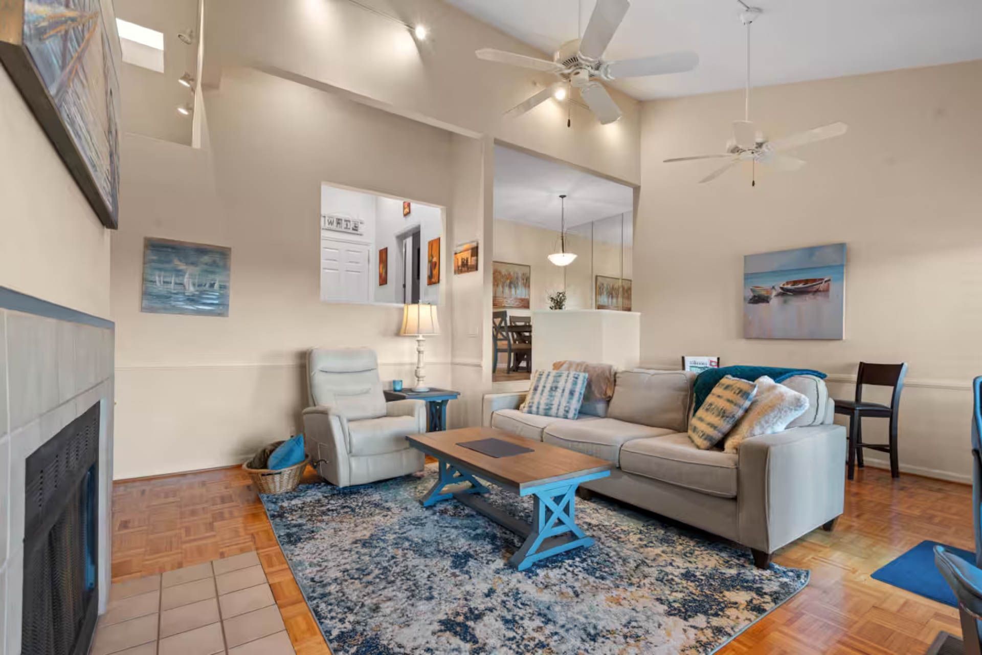 Living room with a fireplace, blue rug, and tan couch.