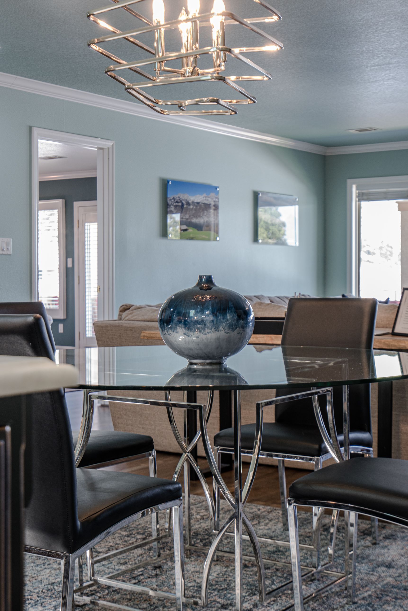 A dining room with a glass table and chairs and a chandelier.