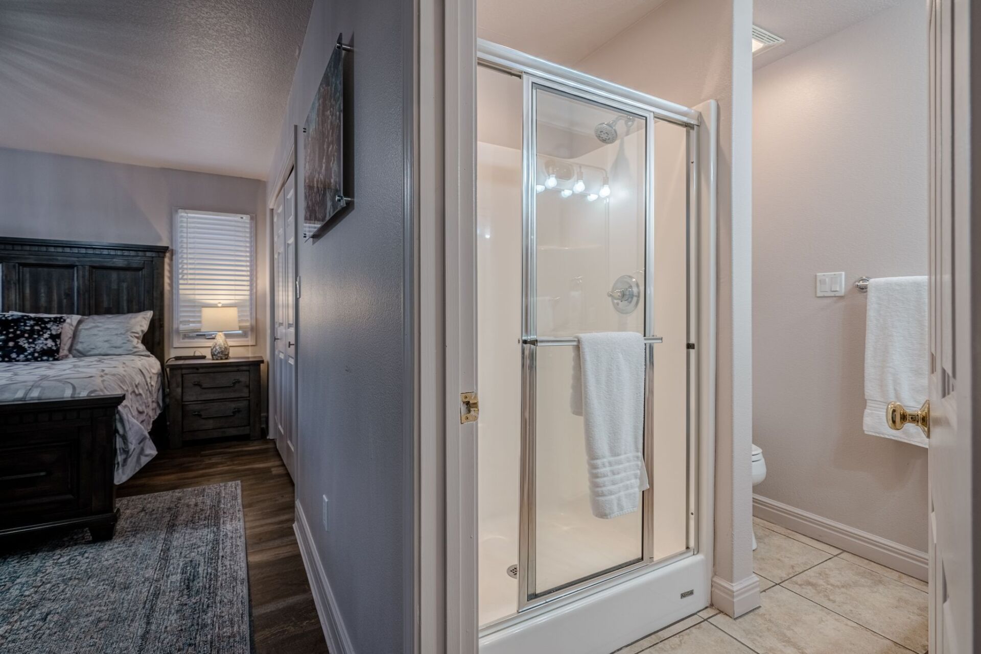 A bathroom with a walk in shower next to a bedroom.