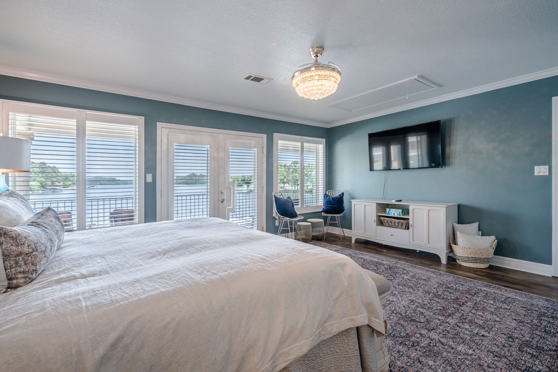 A bedroom with a king size bed , television , and sliding glass doors.
