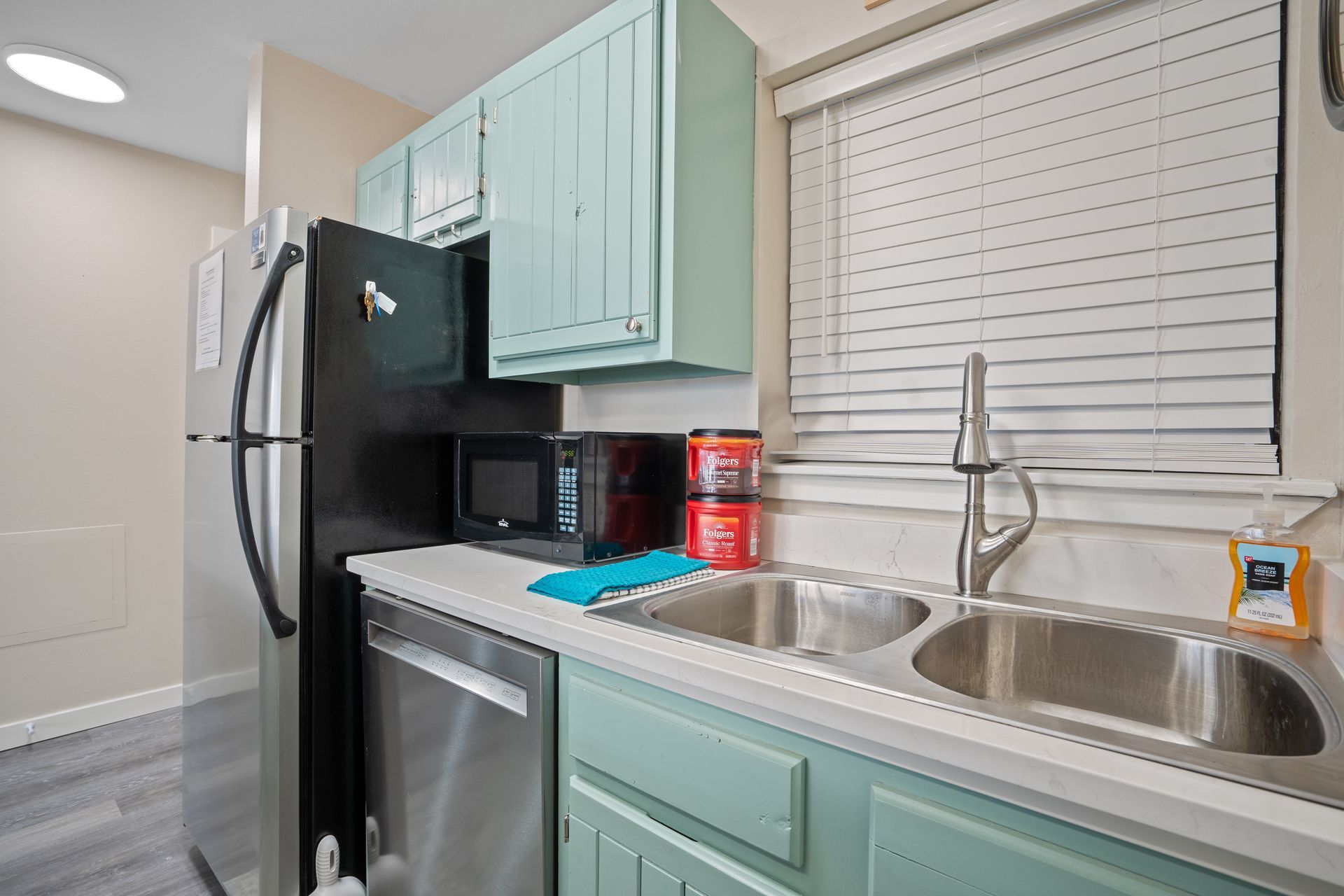 A kitchen with a sink , refrigerator , microwave and dishwasher.