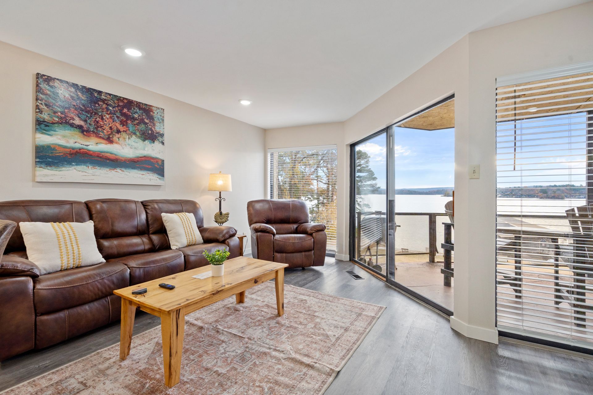 A living room with a couch , chair , coffee table and sliding glass doors leading to a balcony.