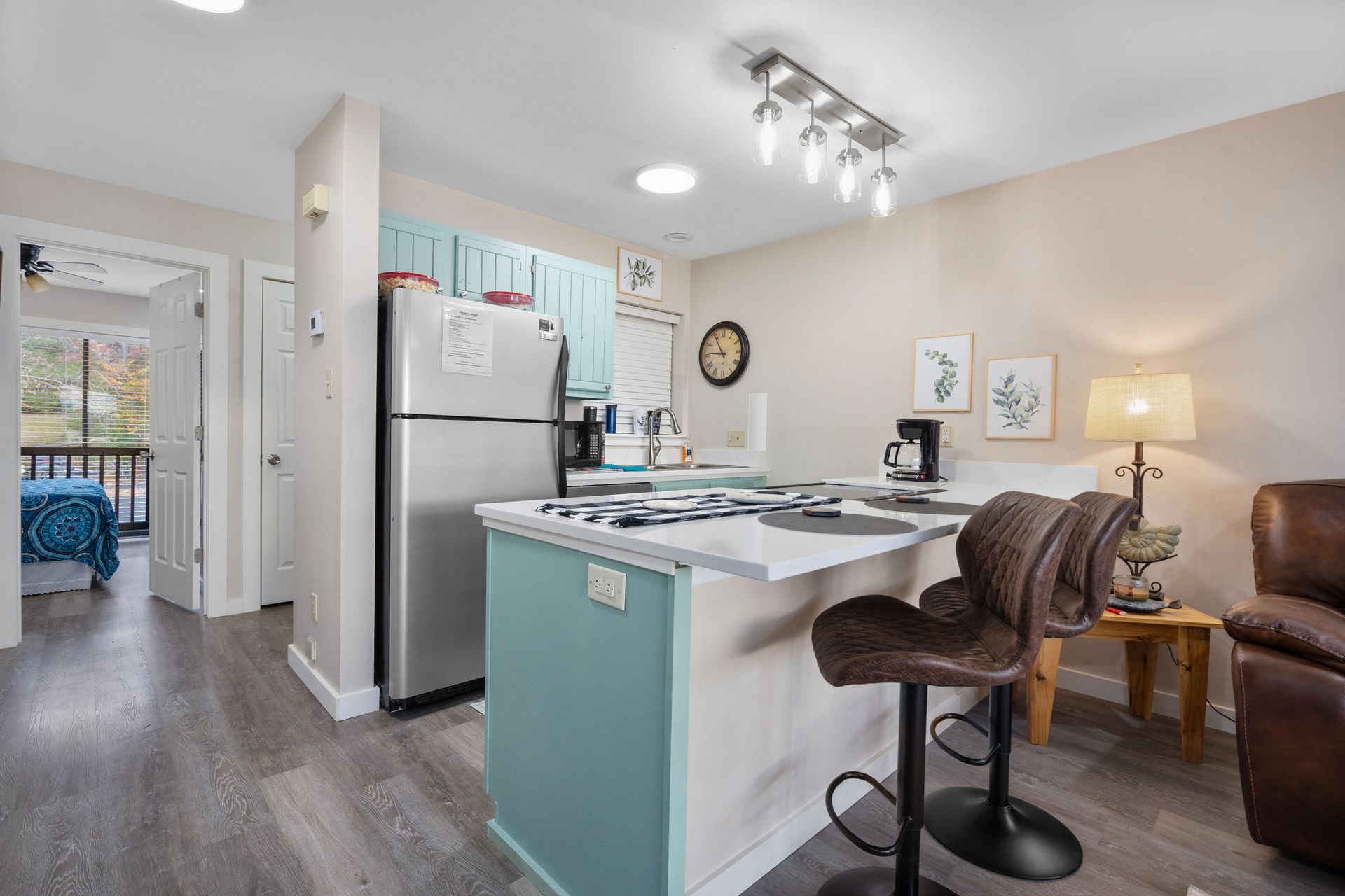 A kitchen with a refrigerator , stove , sink and bar stools.