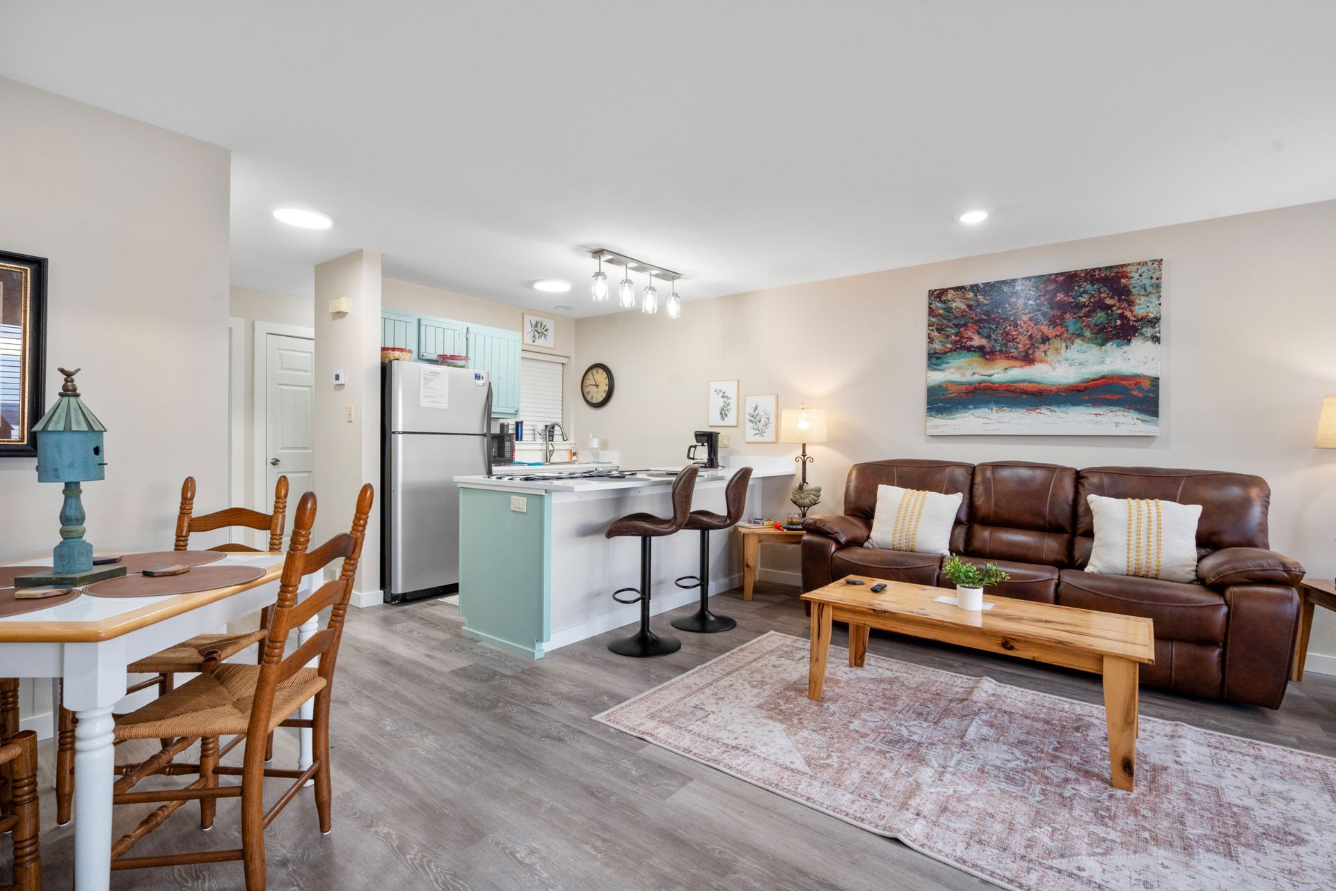 A living room with a couch , table and chairs and a kitchen.