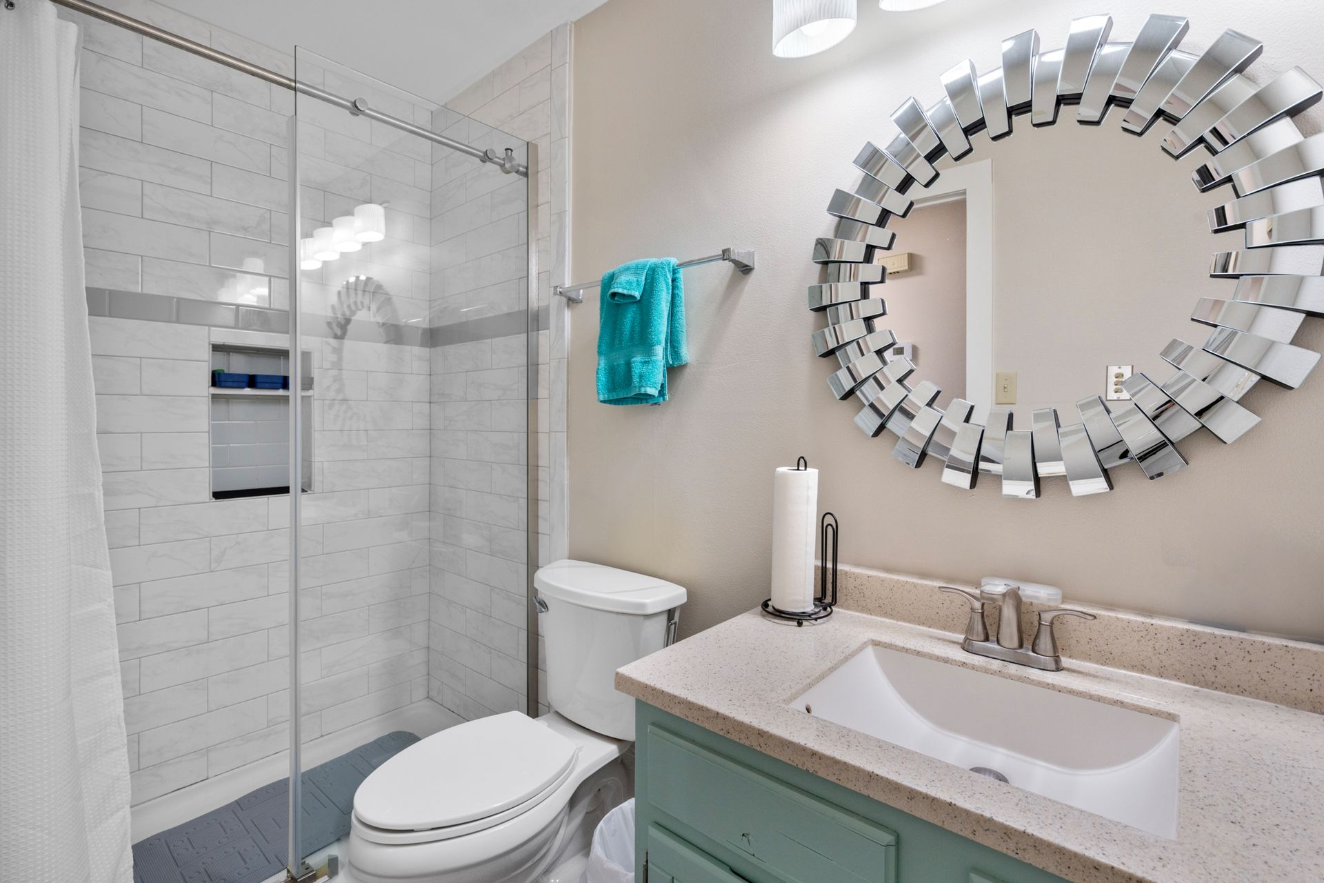 A bathroom with a toilet , sink , mirror and shower.