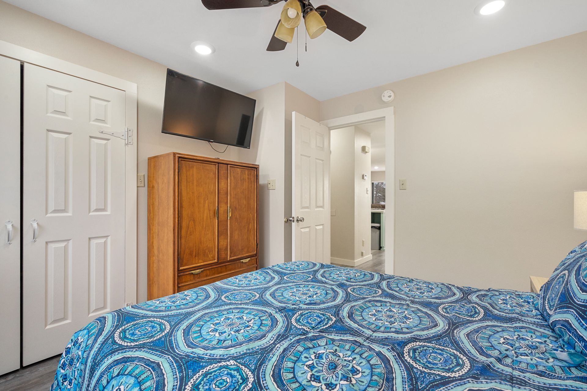 A bedroom with a king size bed , a ceiling fan , and a flat screen tv.