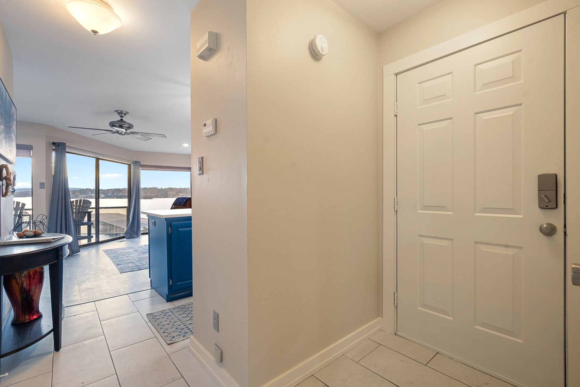 A hallway in a house with a white door and a ceiling fan.