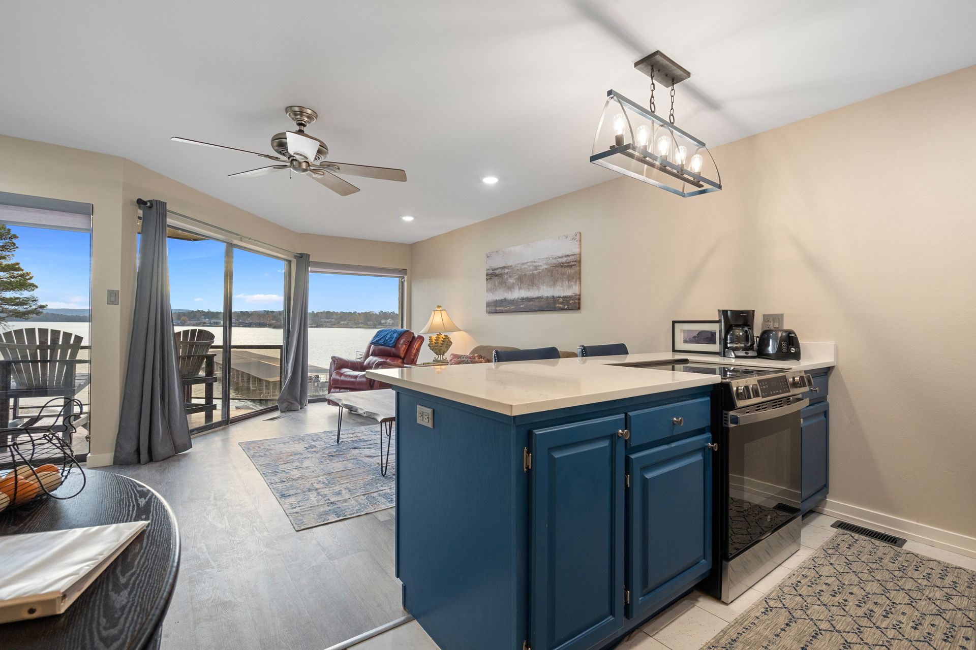 A kitchen with blue cabinets , a stove , and a ceiling fan.