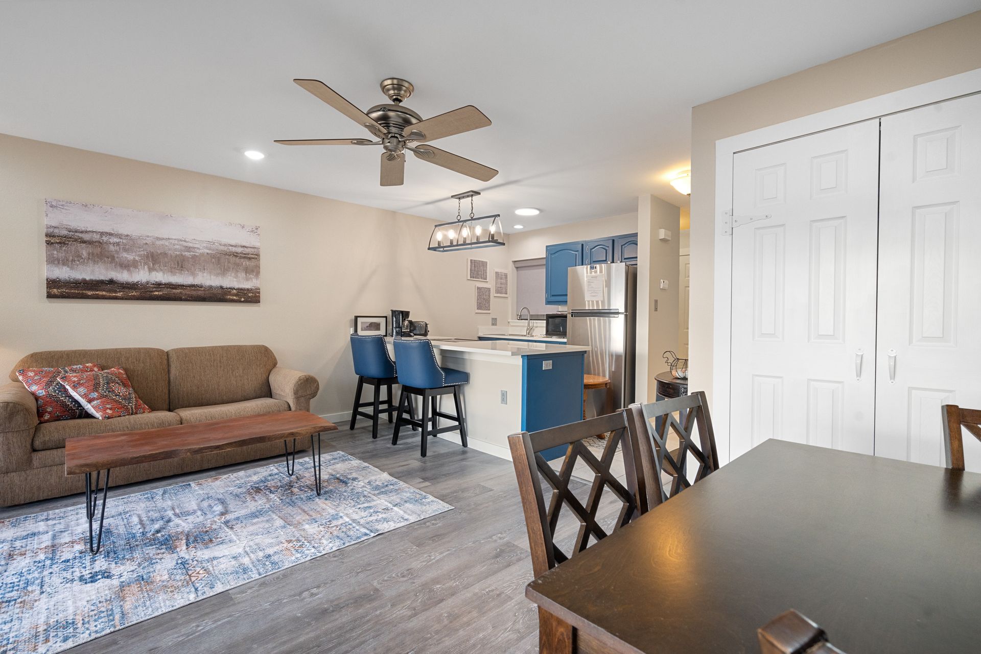 A living room with a couch , table and chairs and a ceiling fan.
