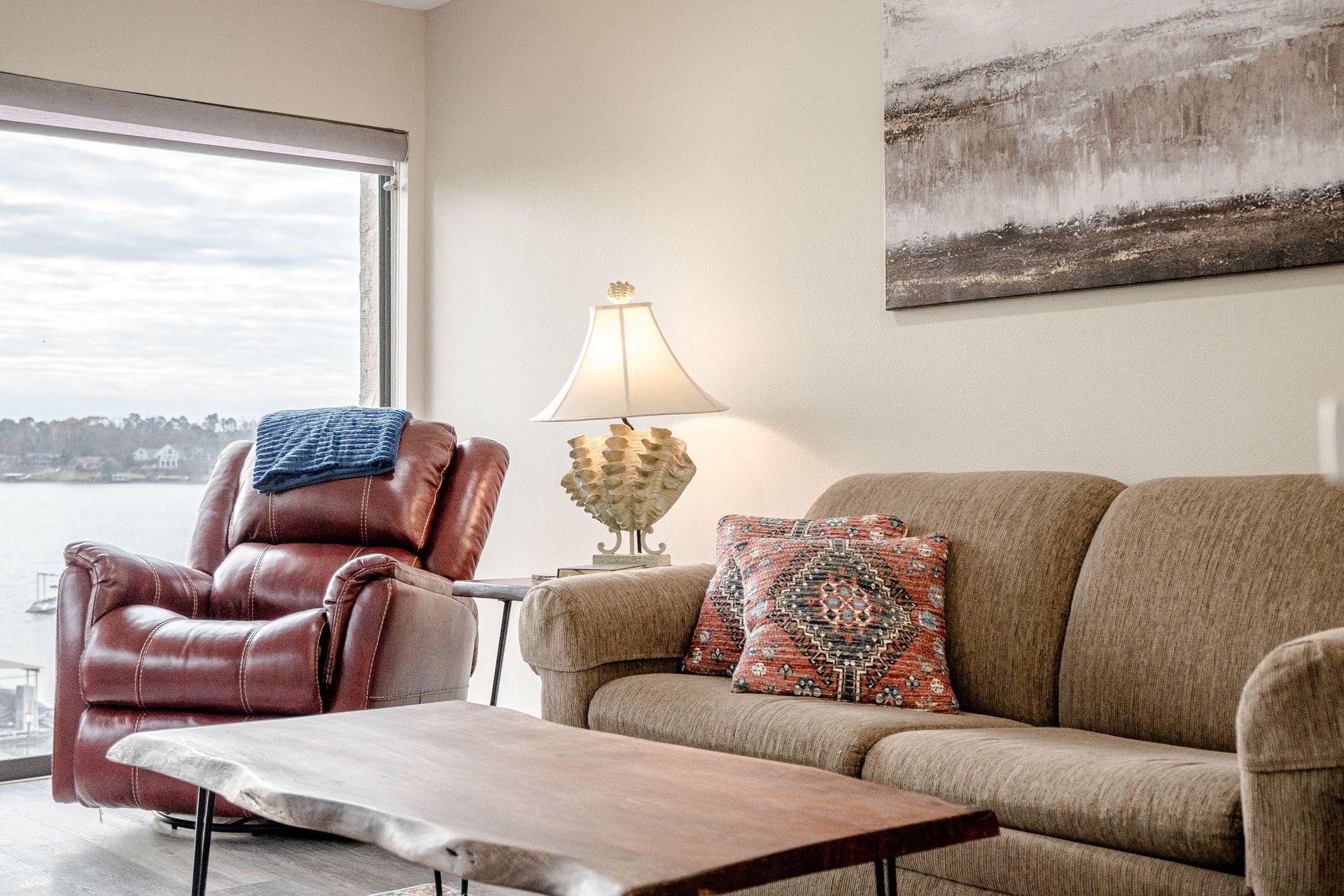 A living room with a couch , chair , coffee table and a large window.