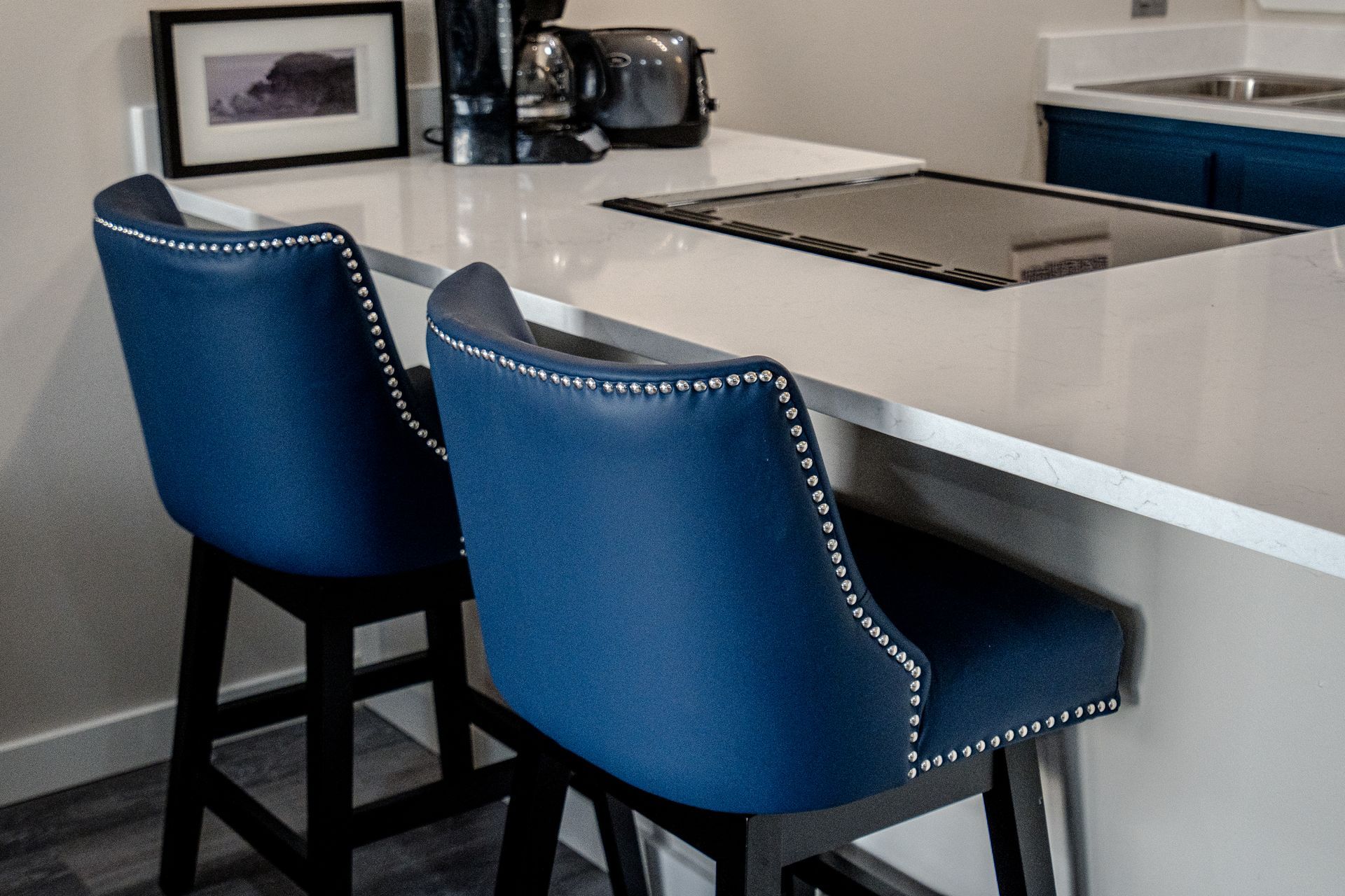 Two blue bar stools are sitting at a counter in a kitchen.
