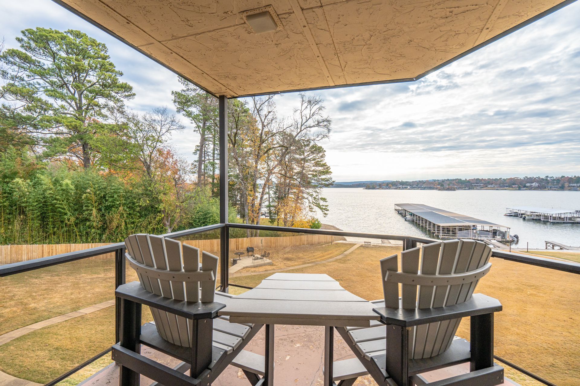 A balcony with two chairs and a table overlooking a lake.