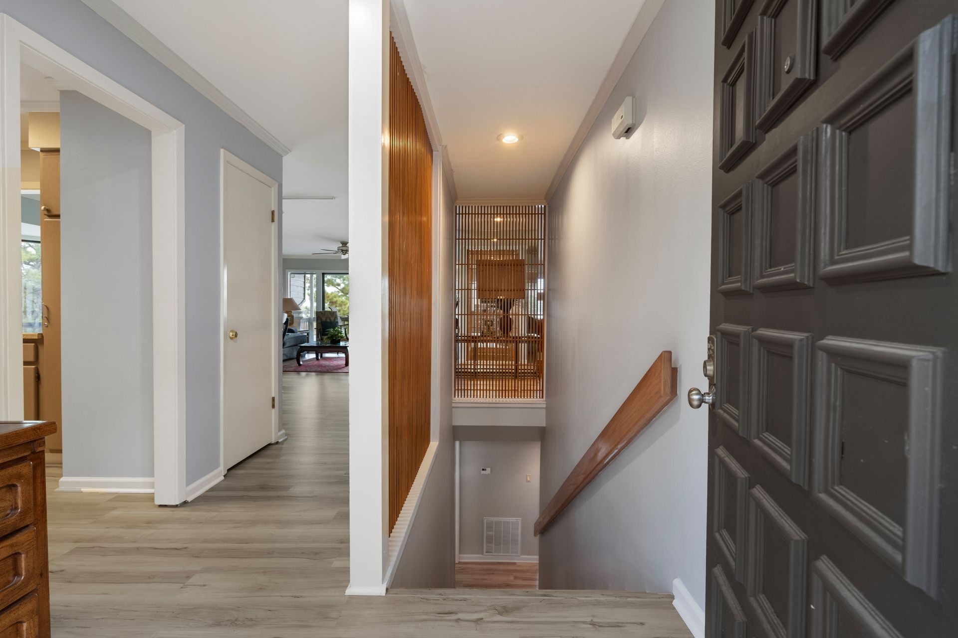A hallway with a black door and stairs leading up to the second floor.