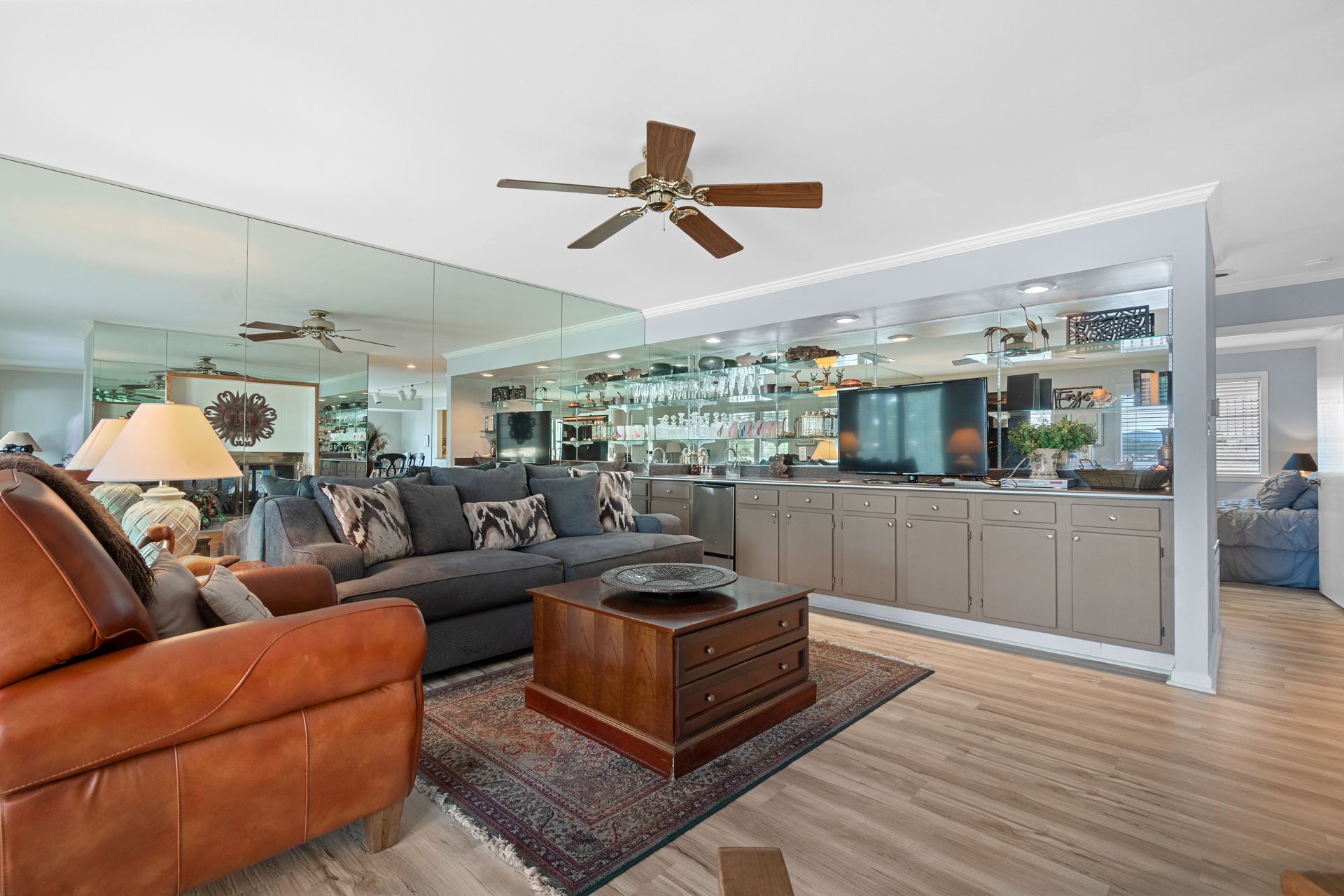 A living room with a couch , chair , coffee table and ceiling fan.