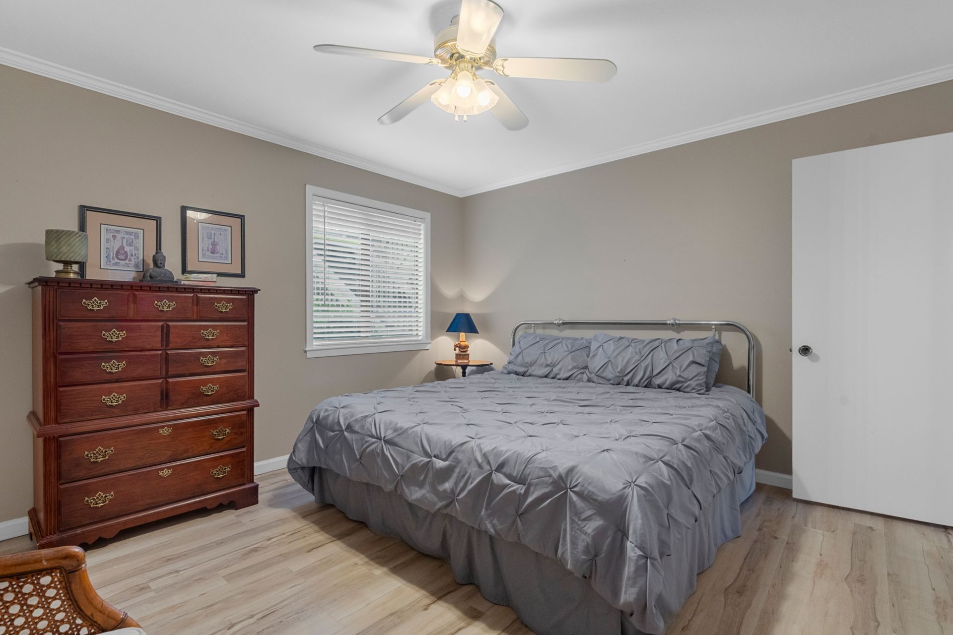 A bedroom with a bed , dresser , and ceiling fan.