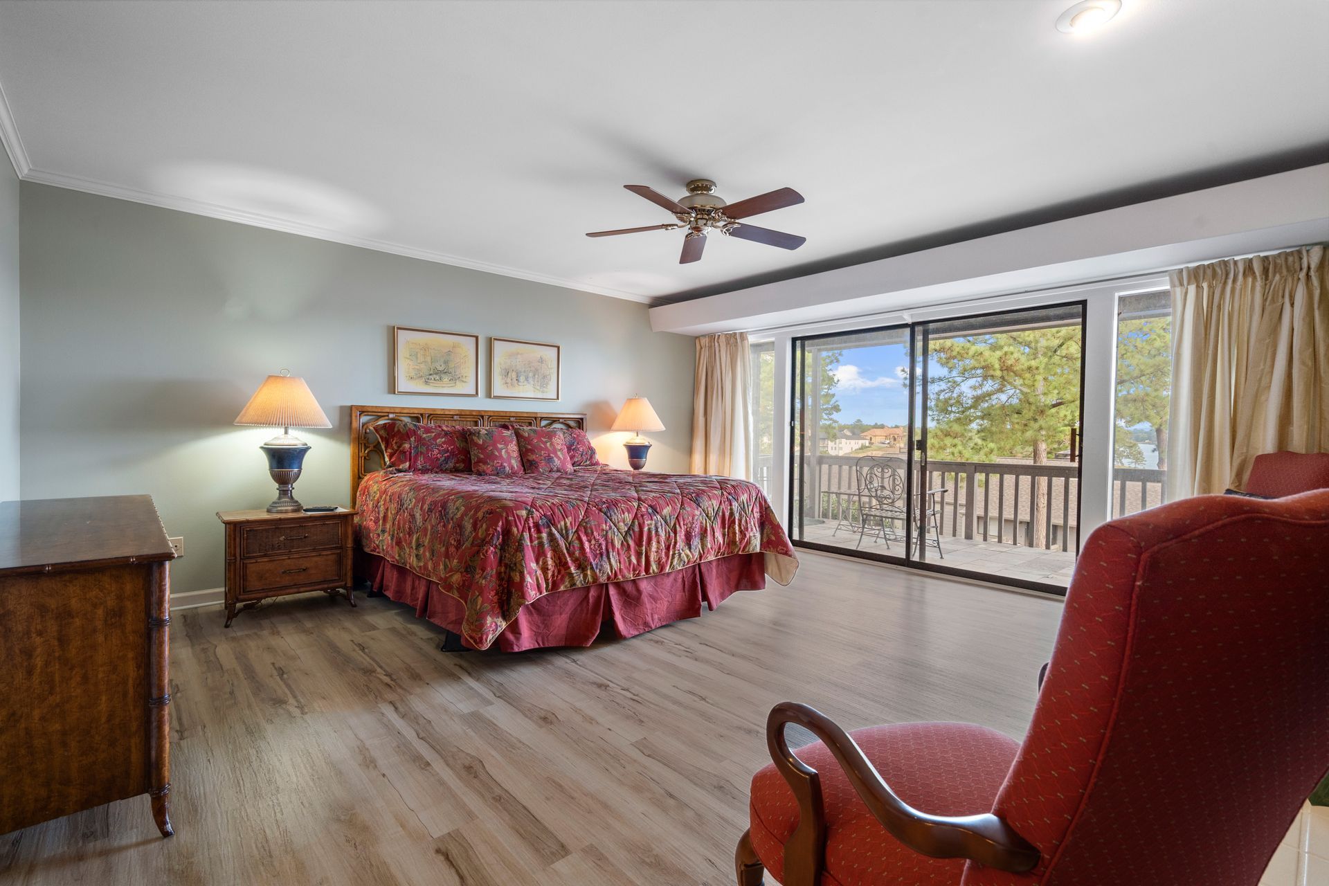 A bedroom with a king size bed , chair , dresser , nightstand and ceiling fan.