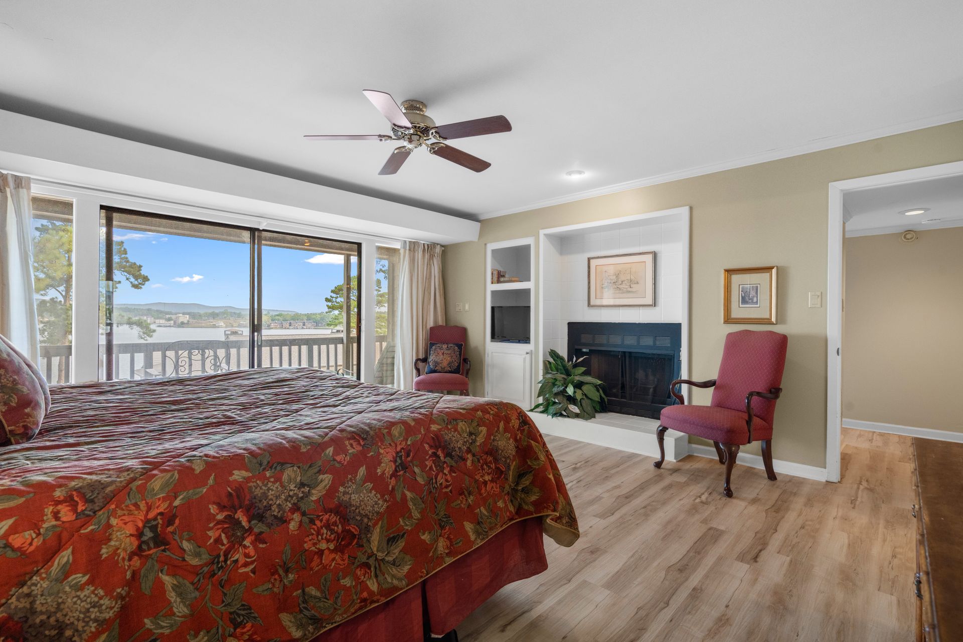 A bedroom with a bed , chair , fireplace and ceiling fan.