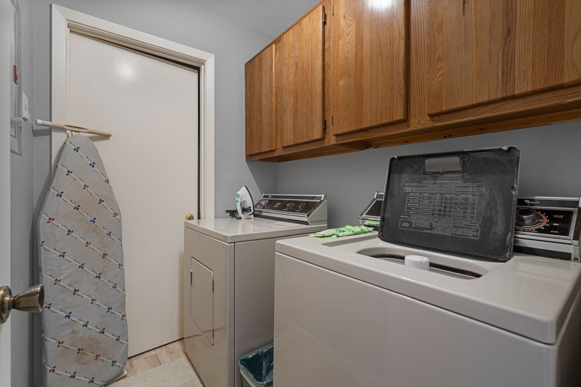 A laundry room with a washer and dryer and an ironing board.