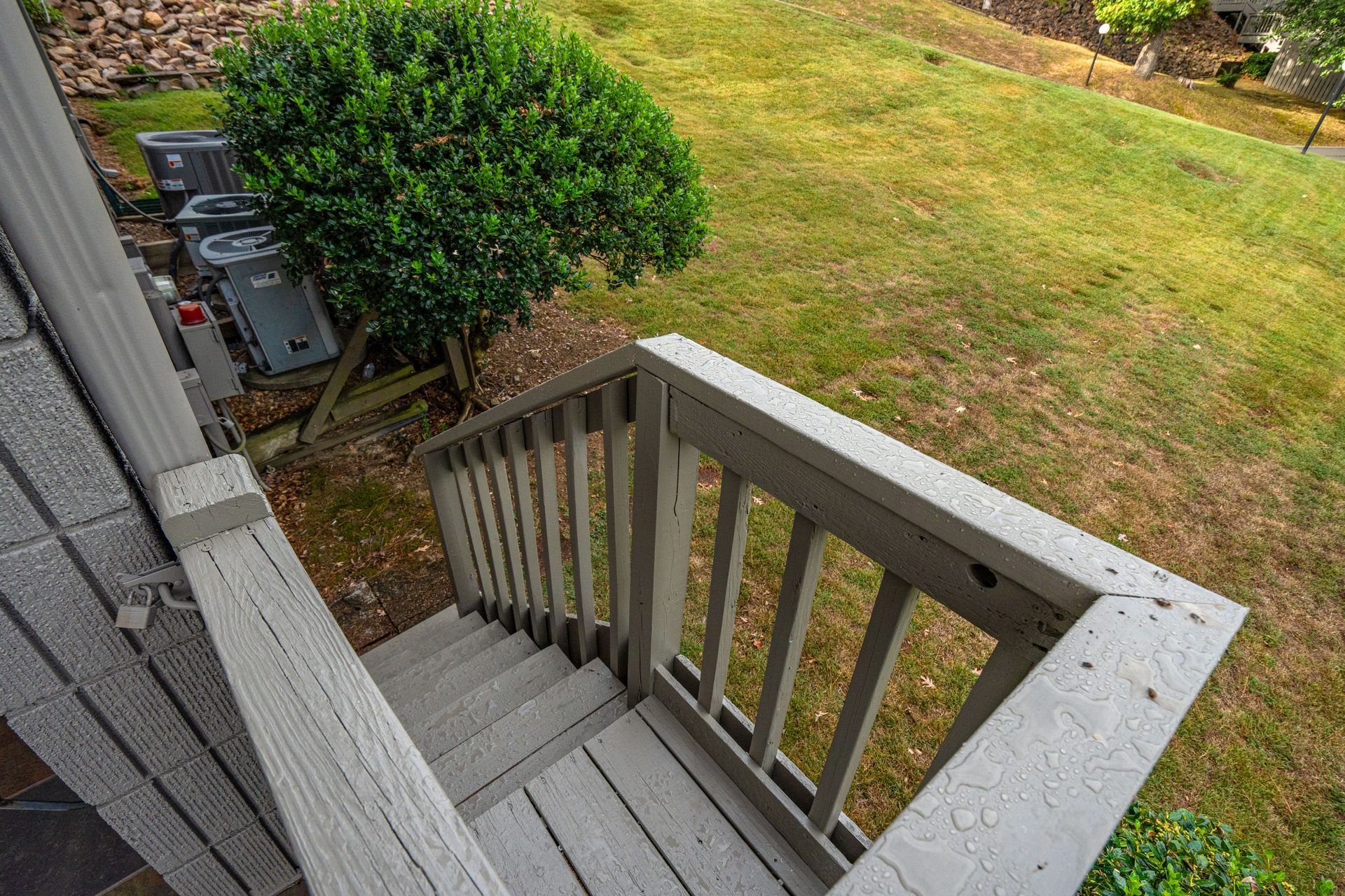 A wooden deck with stairs leading up to a grassy yard.