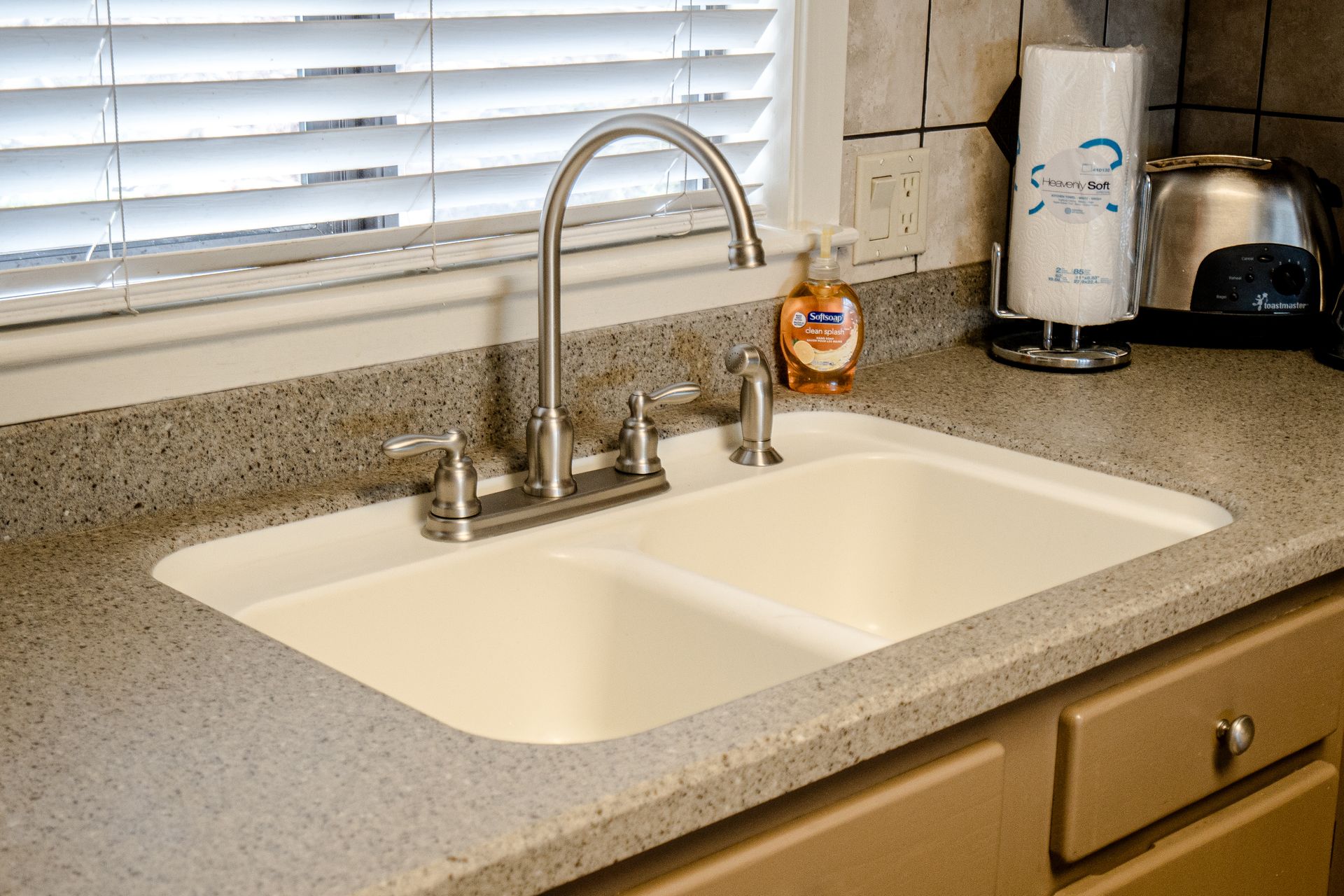 A kitchen sink with a soap dispenser on the counter