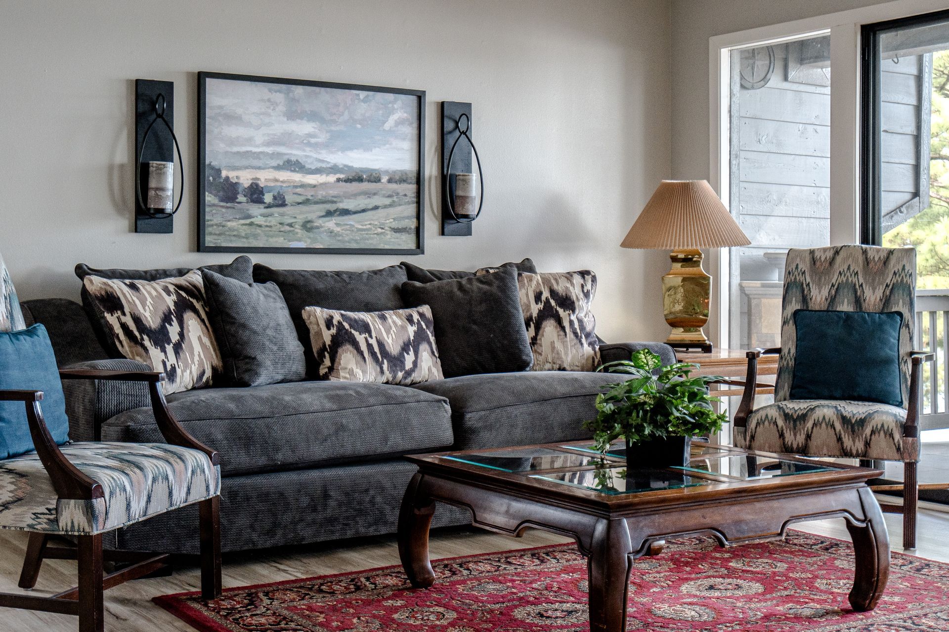 A living room with a couch , chairs , coffee table and paintings on the wall.