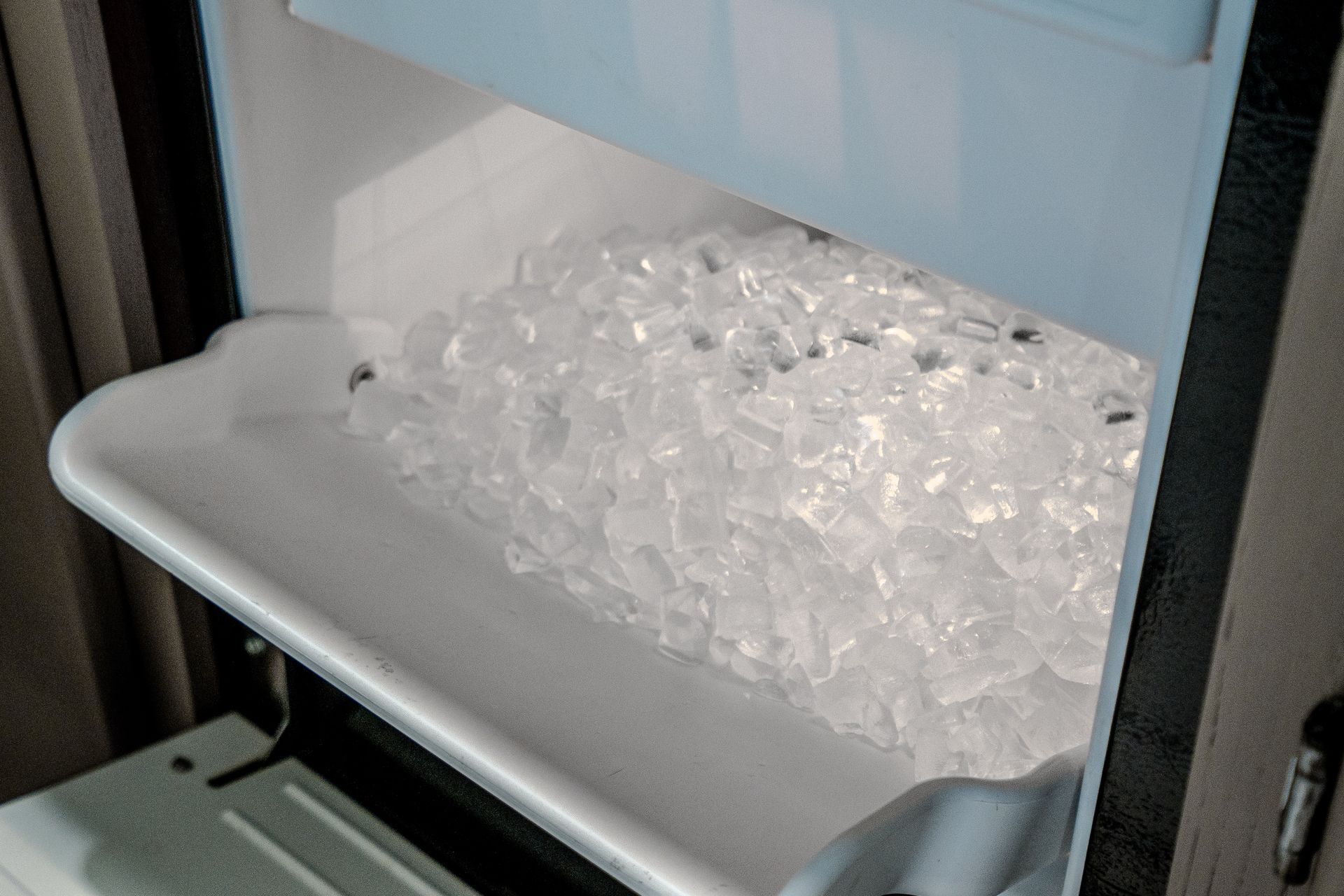 A tray of ice is sitting inside of a refrigerator.
