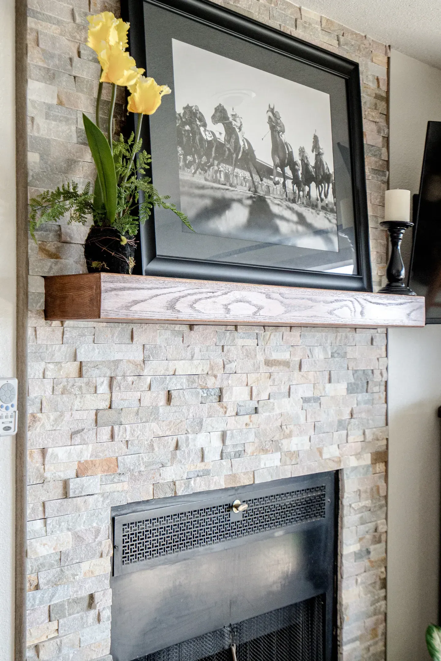 A fireplace with a picture on the mantle and flowers on the mantle.