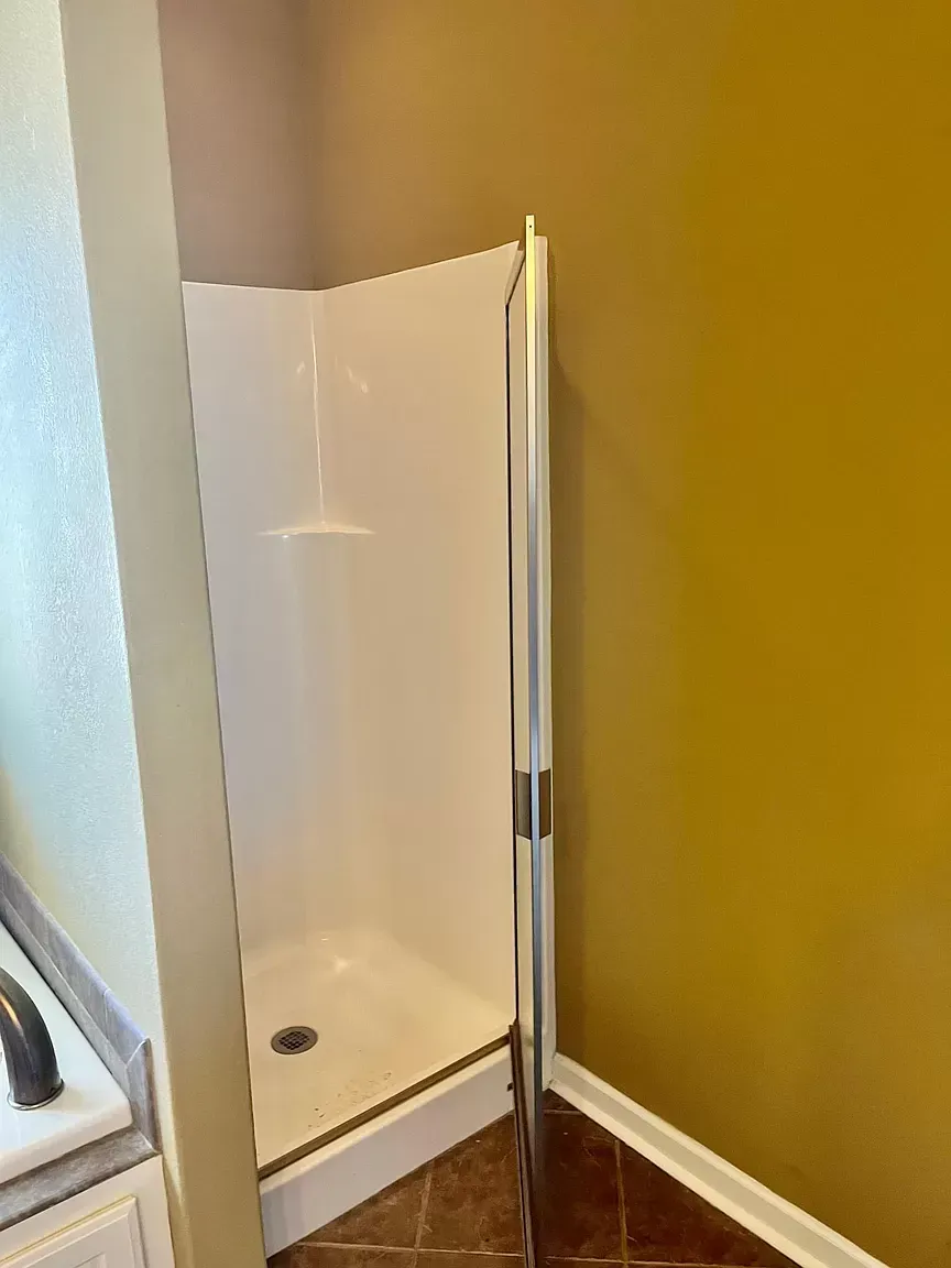 A bathroom with a shower stall and a yellow wall.
