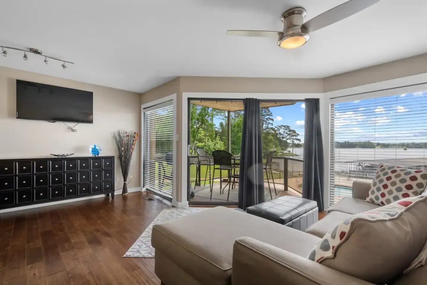 A living room with a couch , ottoman , television and ceiling fan.
