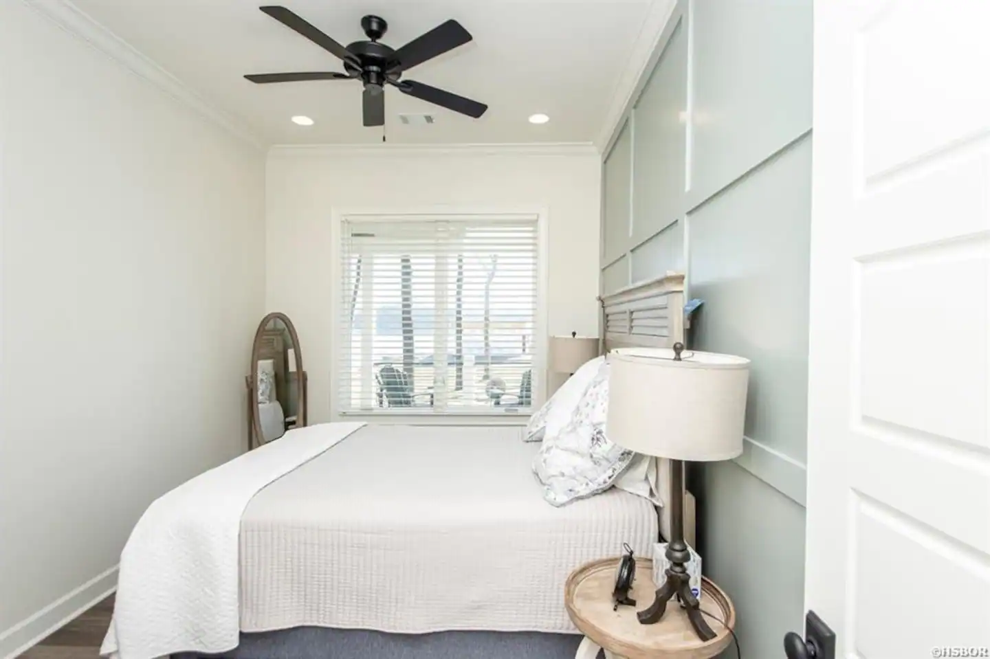 A bedroom with a bed , lamp , and ceiling fan.