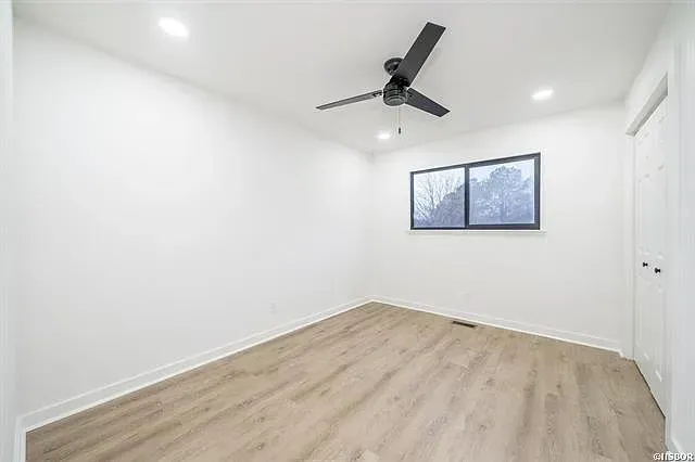 An empty bedroom with a ceiling fan and a window.