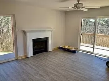 A living room with a fireplace and a ceiling fan.