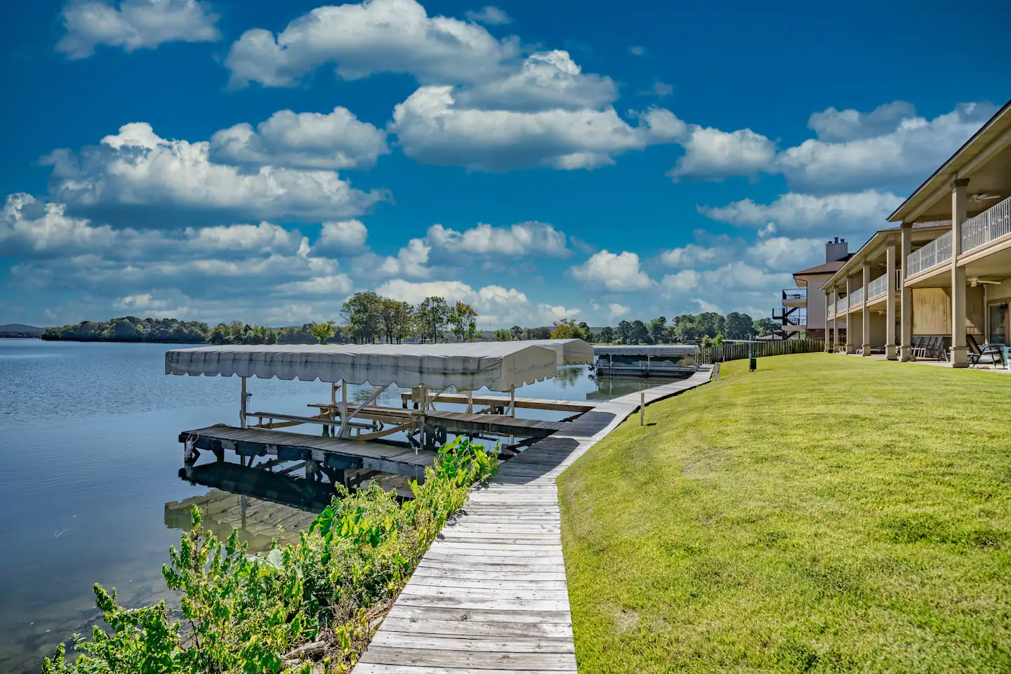 A wooden walkway leading to a dock on the shore of a lake.