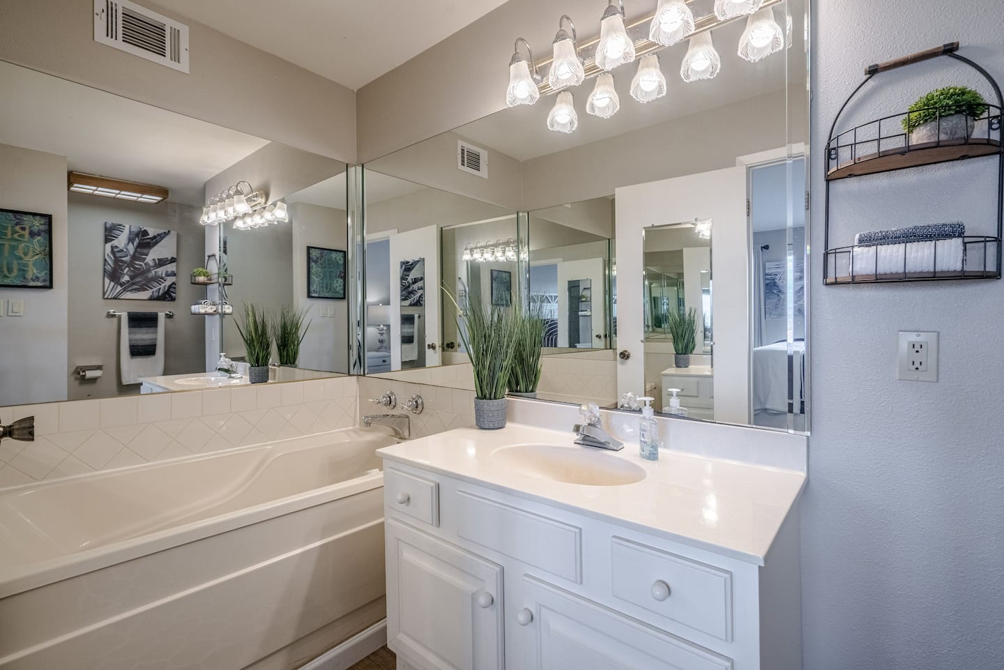 A bathroom with a sink , tub and mirror.