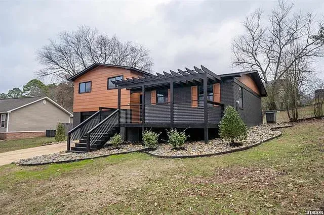 A house with a pergola on the front of it is for sale.