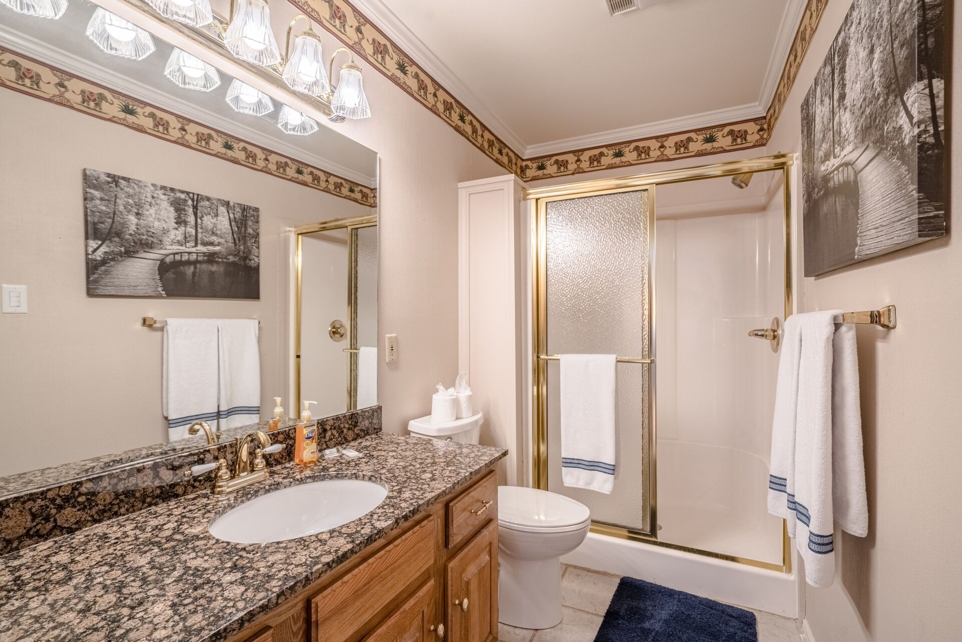 A bathroom with a sink , toilet , shower and mirror.