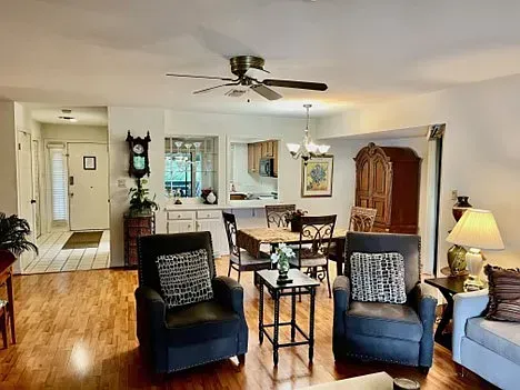 Living room with hardwood floors, two armchairs, a dining table, and a view into the kitchen.